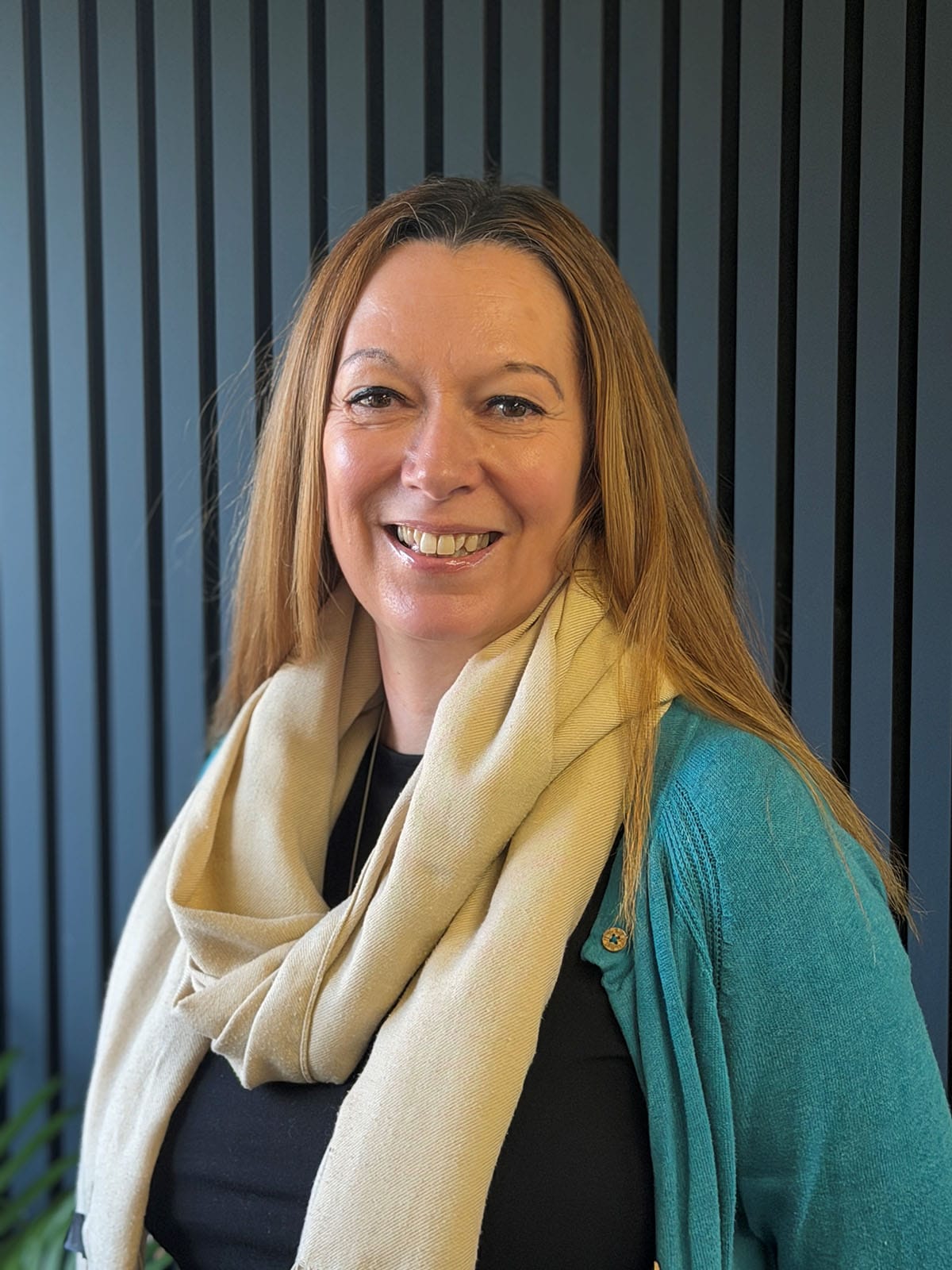 Smiling woman in scarf and teal cardigan