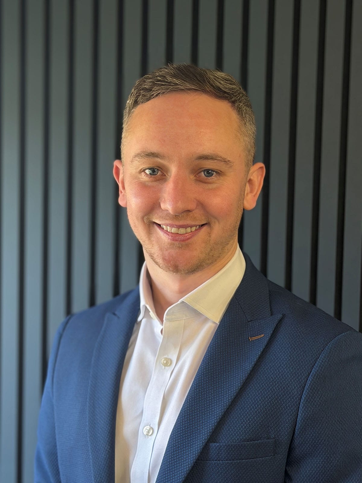 Professional headshot of smiling man in blue suit