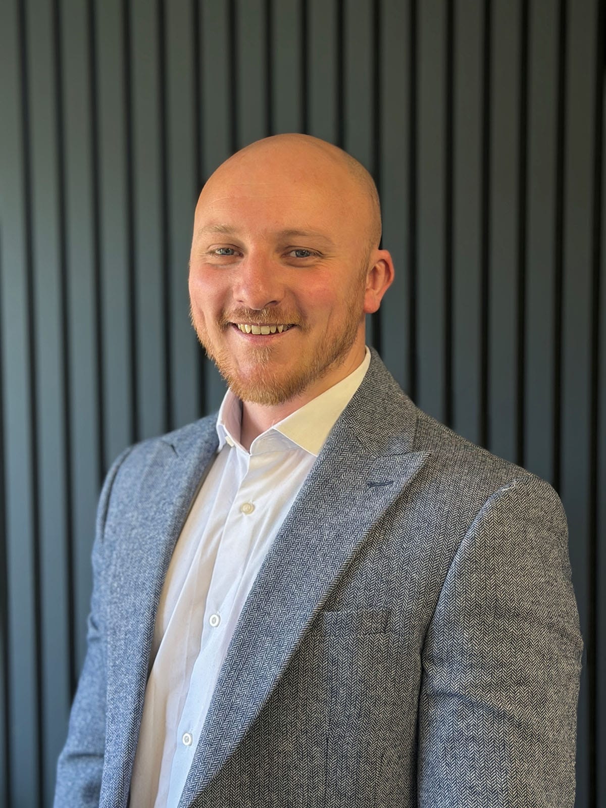Smiling bald man in grey blazer portrait