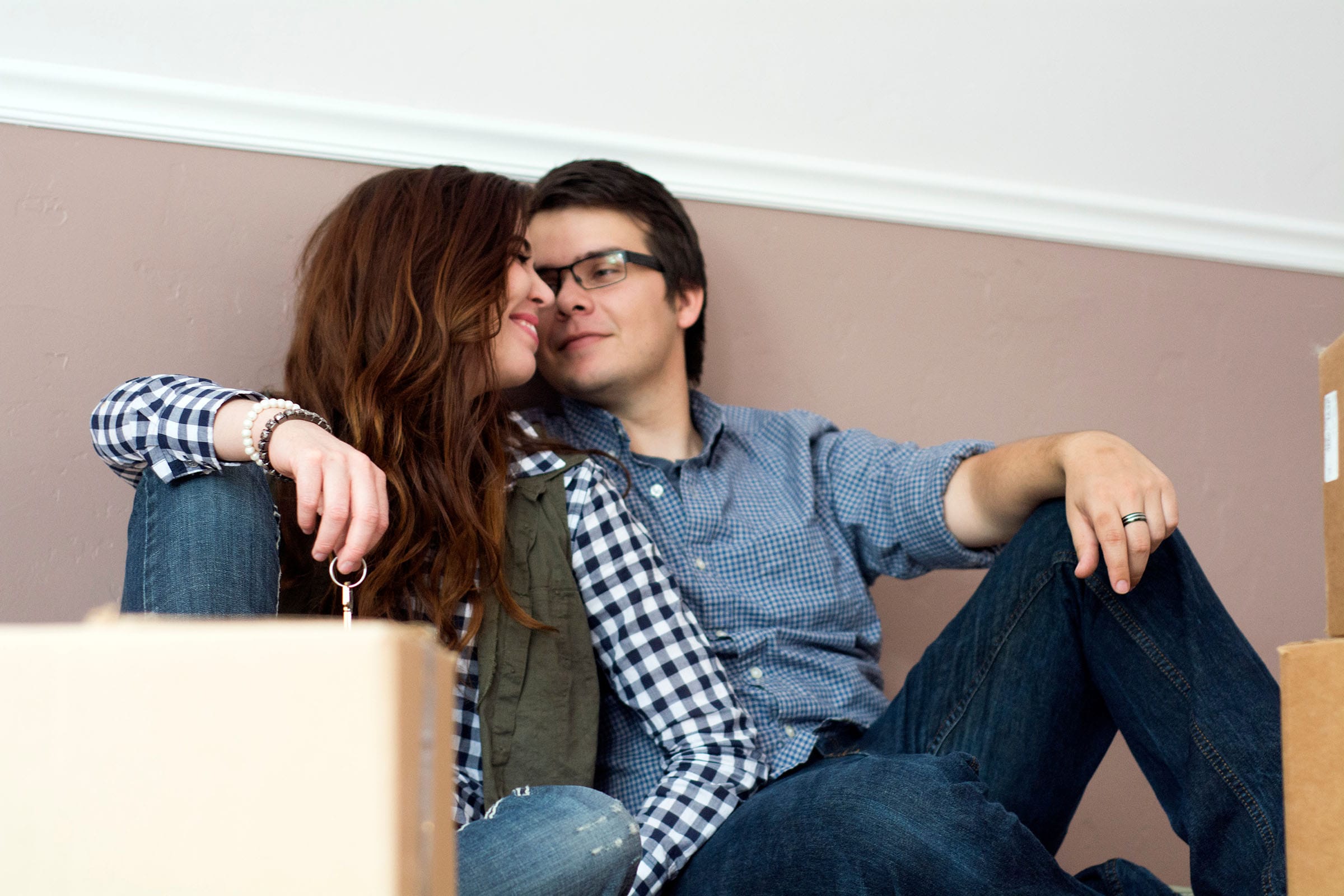 Couple sitting among moving boxes, holding house keys