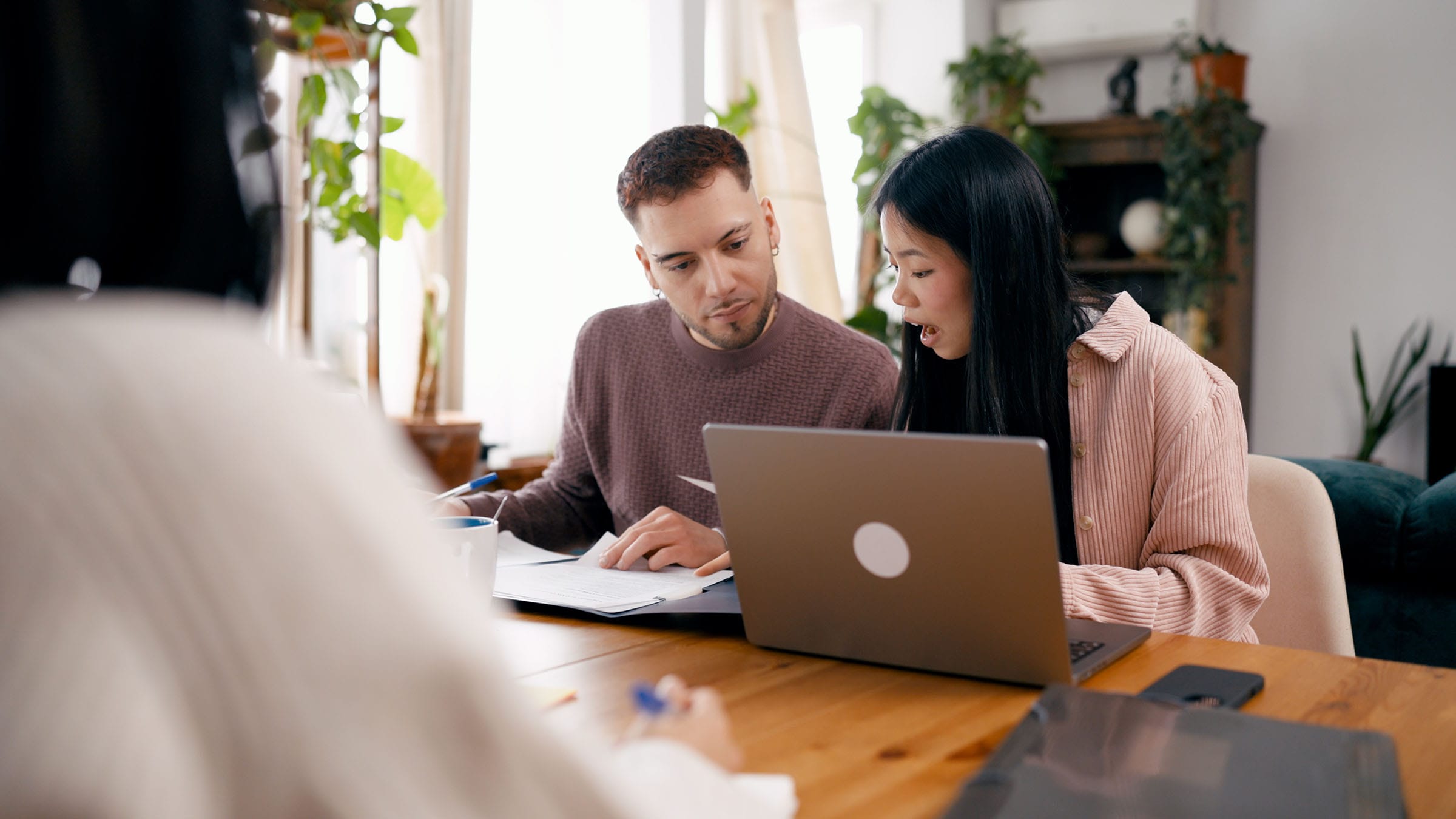 Couple reviewing documents with financial adviser at home